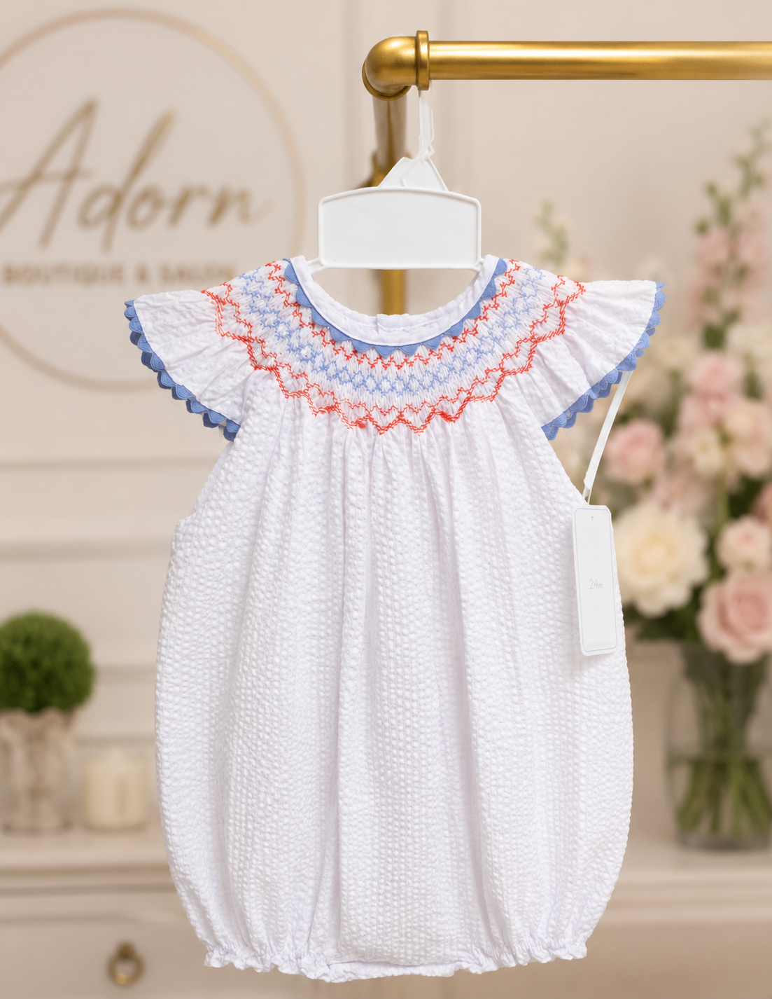White smocked baby romper from Adorn Boutique and Salon